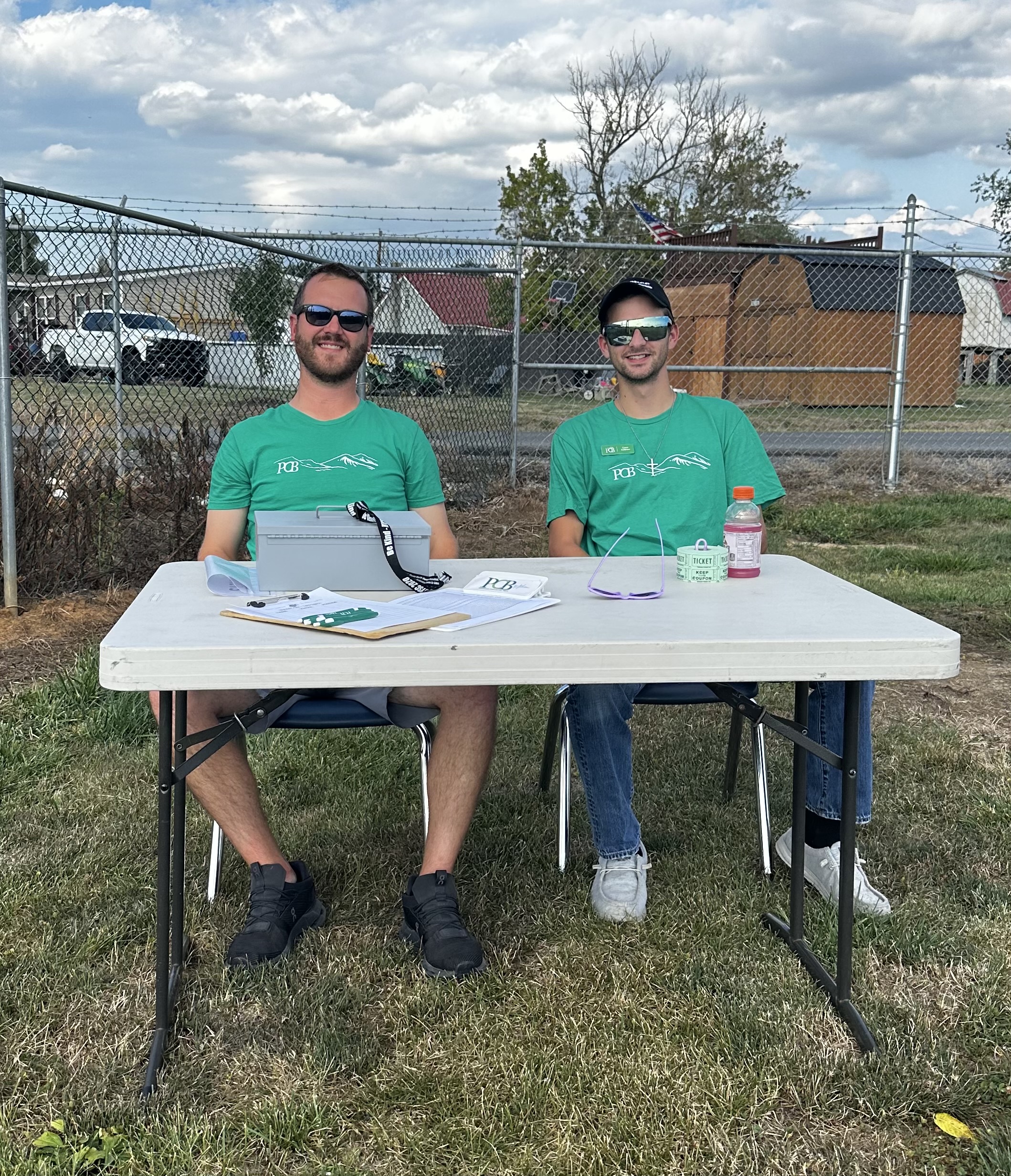 two Moorefield employees sitting outside behind a table. 