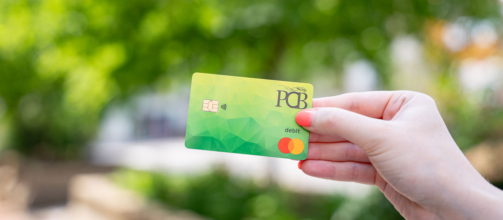 A hand holding a PCB debit card
