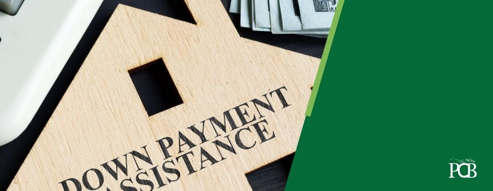 down payment assistance written on a wooden house cutout