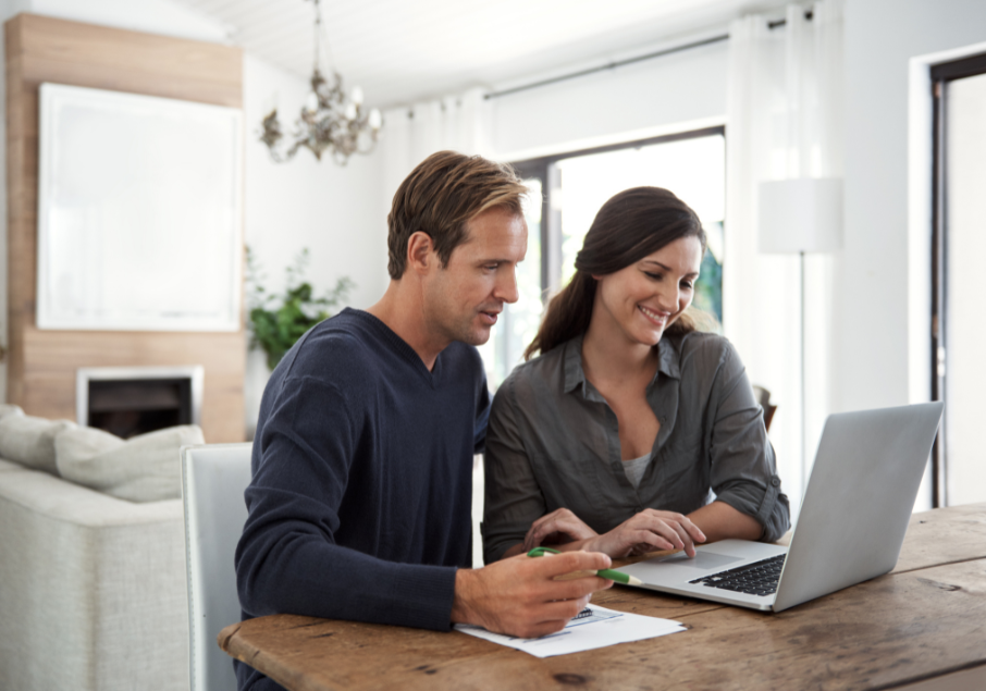 man and woman at the table looking at a laptop.