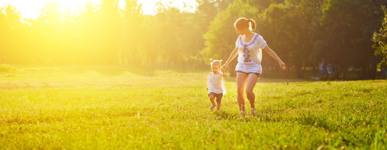 Mother and child running in grassy field